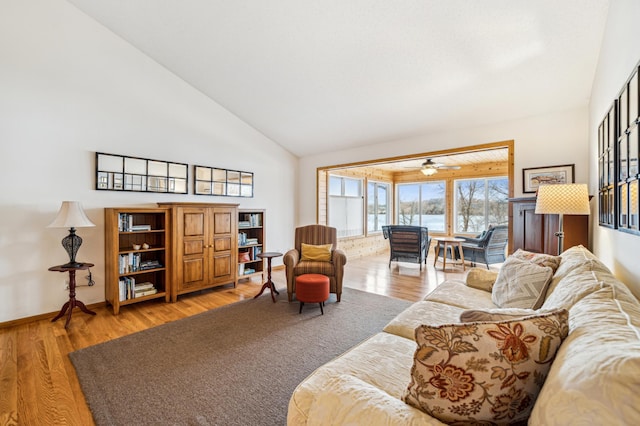 living room with high vaulted ceiling, baseboards, and light wood finished floors