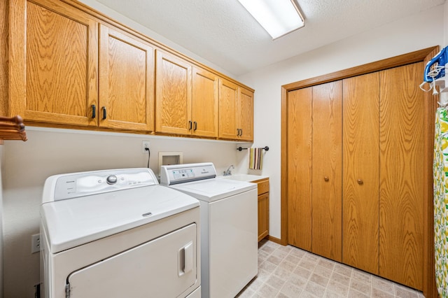 laundry area featuring washer and dryer, cabinet space, a textured ceiling, and light floors