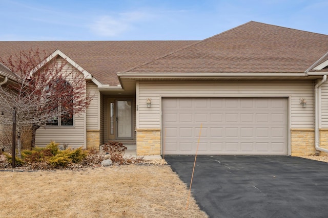 single story home with a garage, driveway, and roof with shingles