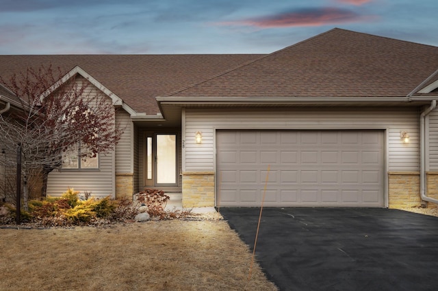 view of front of property with aphalt driveway, stone siding, a shingled roof, and an attached garage