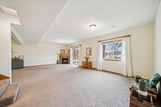 sitting room featuring a textured ceiling, carpet floors, a tiled fireplace, and baseboards