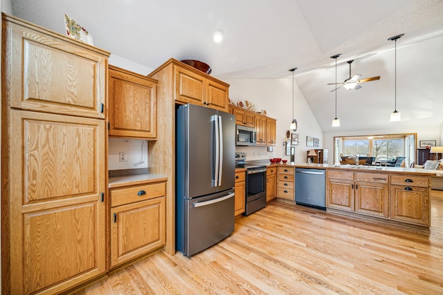 kitchen featuring appliances with stainless steel finishes, vaulted ceiling, a sink, light wood-type flooring, and a peninsula