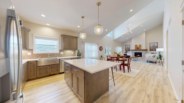 kitchen featuring appliances with stainless steel finishes, a center island, a kitchen bar, a fireplace, and a sink