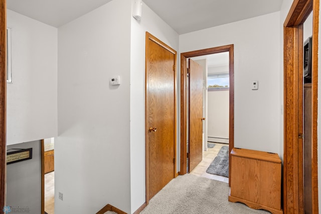 hallway with a baseboard heating unit and light carpet