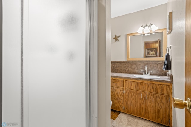 bathroom featuring a shower with shower door, vanity, and backsplash