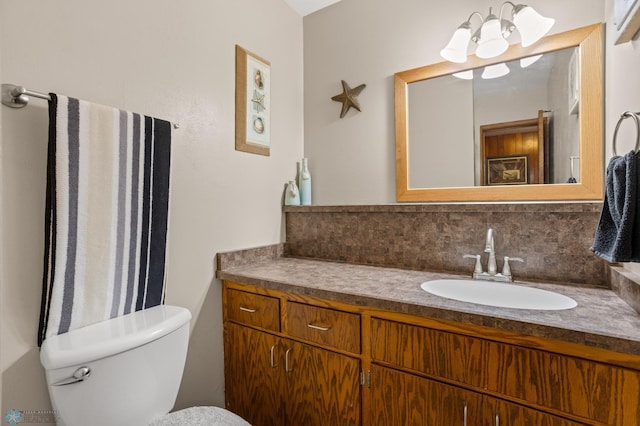 bathroom with toilet, vanity, and decorative backsplash