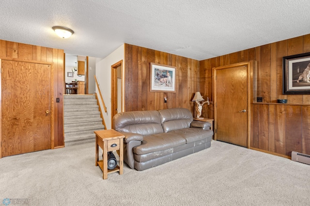 carpeted living room with baseboard heating, wood walls, and a textured ceiling