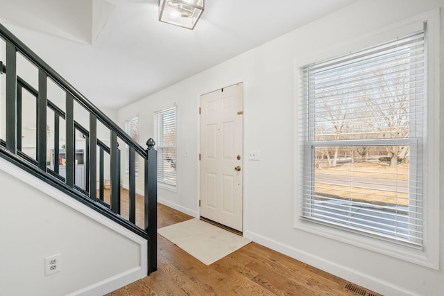 entrance foyer with stairs, visible vents, wood finished floors, and baseboards