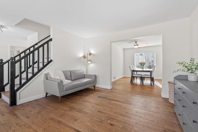 living area with stairway, baseboards, ceiling fan, and wood finished floors