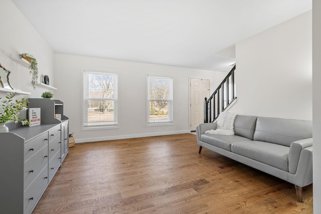 living room with baseboards, stairs, and light wood-style floors