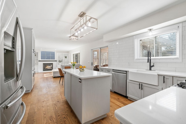 kitchen with tasteful backsplash, a center island, light wood-type flooring, stainless steel appliances, and a sink