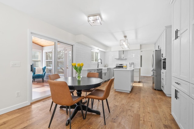 dining space featuring light wood-type flooring and baseboards