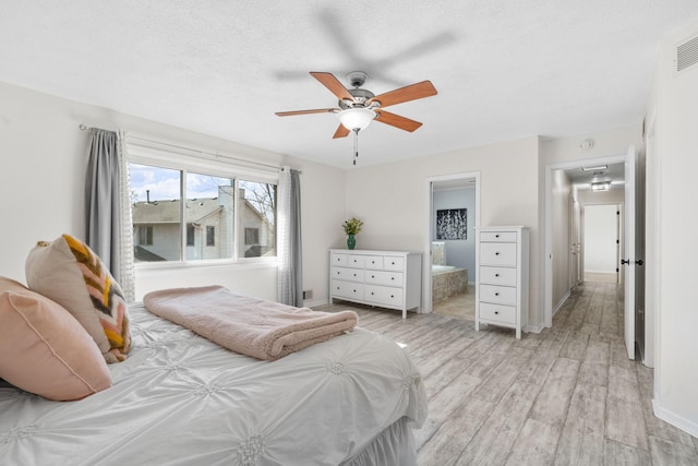 bedroom featuring visible vents, baseboards, attic access, light wood-type flooring, and ensuite bath