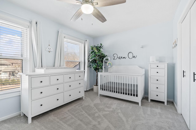 bedroom featuring baseboards, light carpet, and a crib