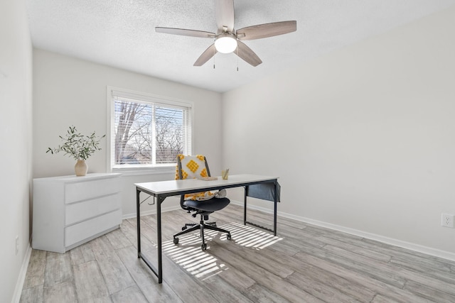 office space featuring ceiling fan, baseboards, a textured ceiling, and light wood-style flooring