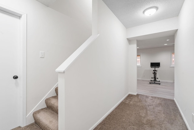 stairs with baseboards, carpet, and a textured ceiling