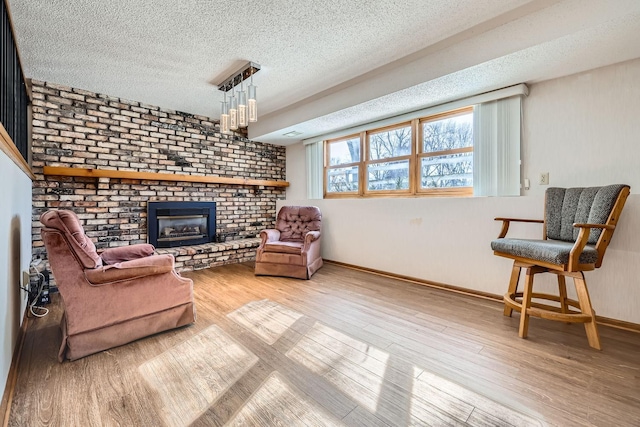 living area with a textured ceiling, a fireplace, and light hardwood / wood-style flooring