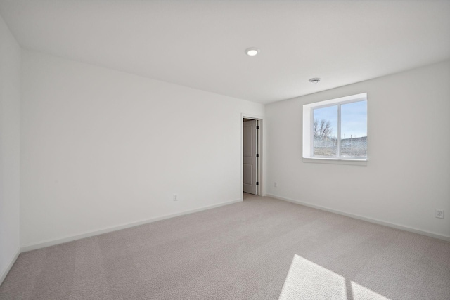 unfurnished room featuring baseboards and light colored carpet