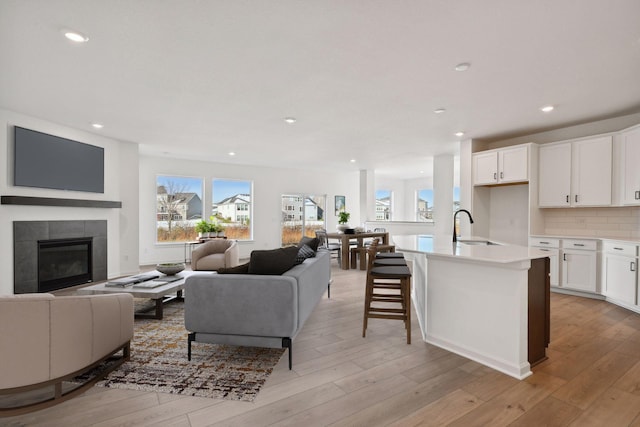 kitchen featuring light wood finished floors, open floor plan, white cabinets, and a sink