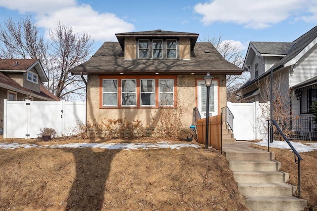 bungalow with fence and stucco siding