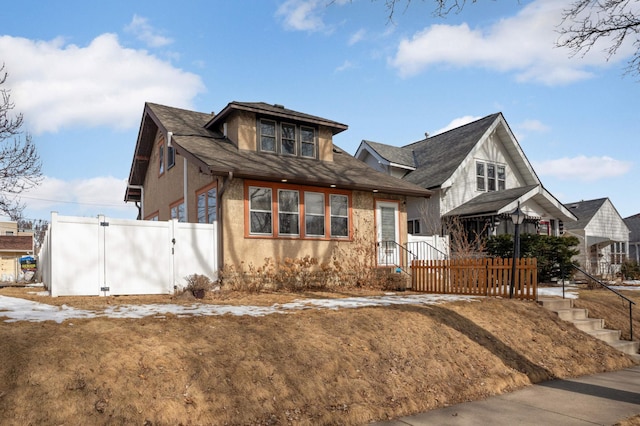 view of front facade featuring a gate, stucco siding, and fence