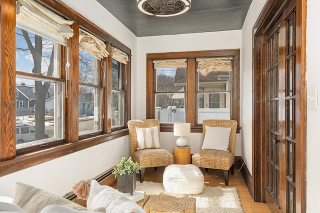 living area featuring baseboard heating, light wood-type flooring, and baseboards