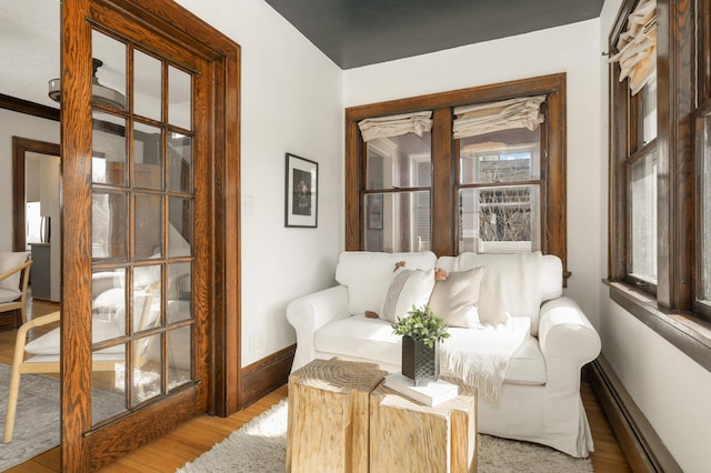 sitting room with light wood-type flooring, a baseboard heating unit, and baseboards