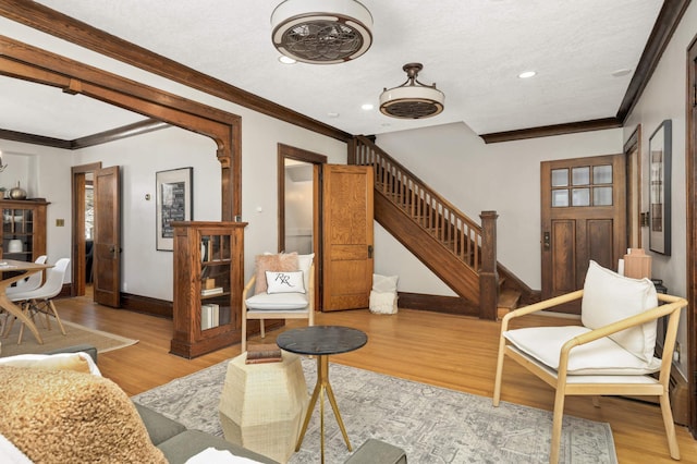 living room featuring stairway, baseboards, recessed lighting, ornamental molding, and light wood-style floors