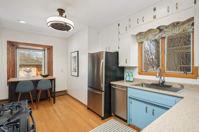 kitchen featuring white cabinets, stainless steel appliances, light countertops, and a sink