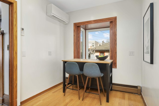 dining space featuring light wood-type flooring, a wall mounted AC, and baseboards