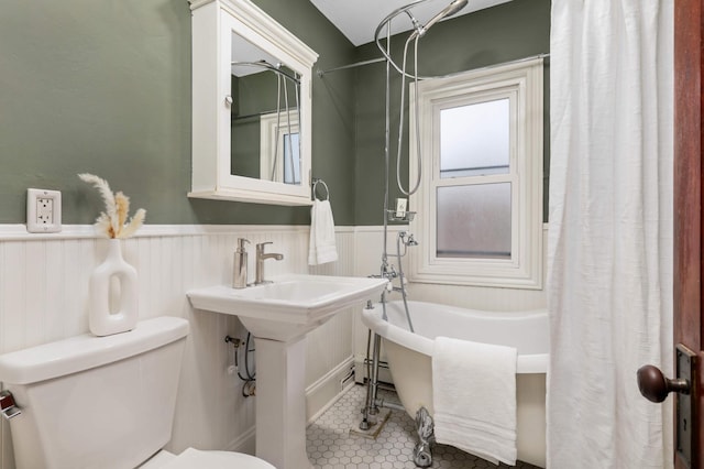 bathroom featuring tile patterned floors, wainscoting, and toilet