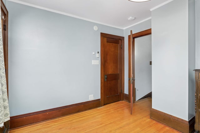 unfurnished bedroom with light wood finished floors, crown molding, and baseboards