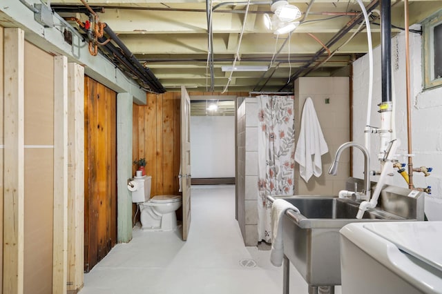 unfinished basement featuring concrete block wall and a sink