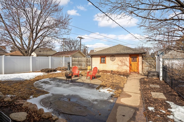 exterior space featuring stucco siding, an outdoor structure, roof with shingles, and a fenced backyard