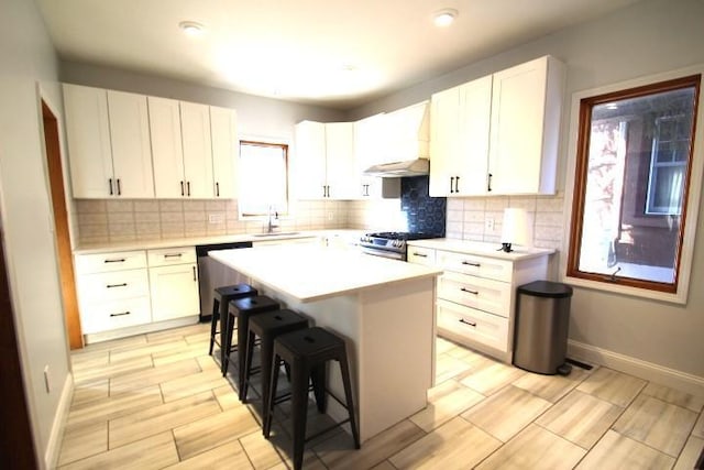 kitchen with backsplash, a kitchen breakfast bar, a center island, stainless steel appliances, and white cabinets