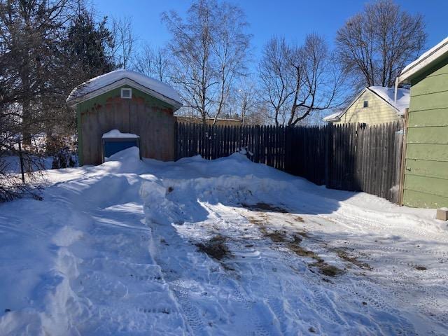 yard layered in snow featuring a shed