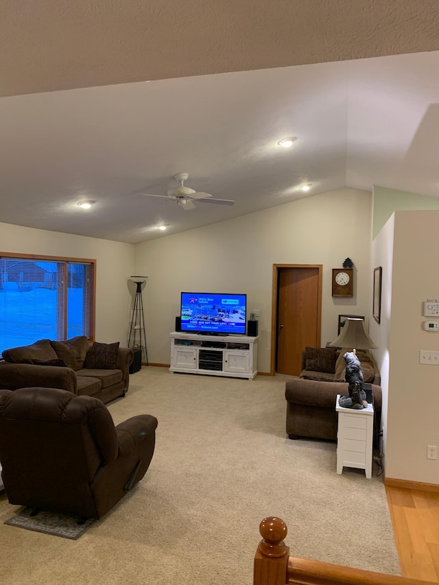 carpeted living room with ceiling fan and vaulted ceiling