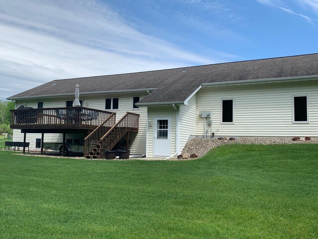 rear view of property featuring a lawn, roof with shingles, a deck, and stairs