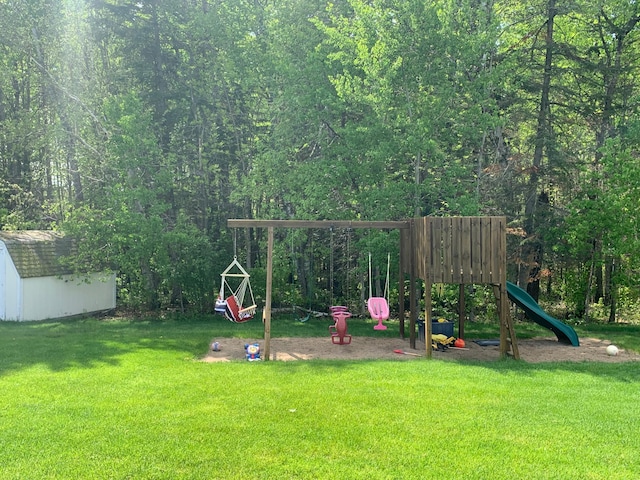 view of playground featuring a lawn, a storage unit, and an outdoor structure