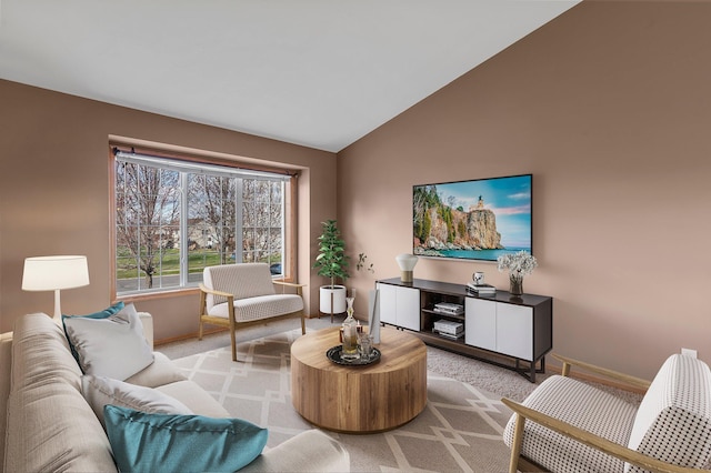 living area featuring baseboards, light colored carpet, and lofted ceiling