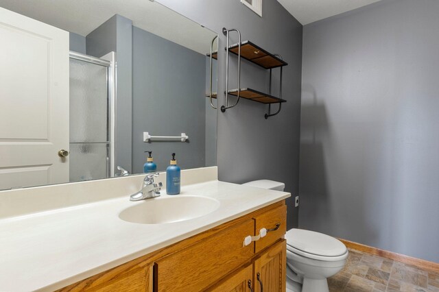 bathroom featuring vanity, visible vents, toilet, baseboards, and a shower stall