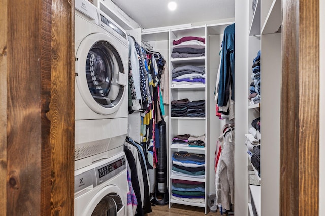 washroom featuring laundry area, wood finished floors, and stacked washer and clothes dryer