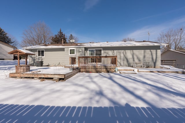 snow covered rear of property with cooling unit and a wooden deck