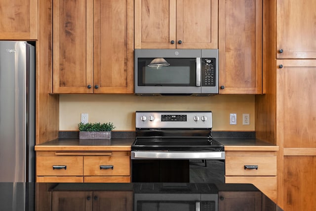 kitchen featuring dark countertops, appliances with stainless steel finishes, and brown cabinetry