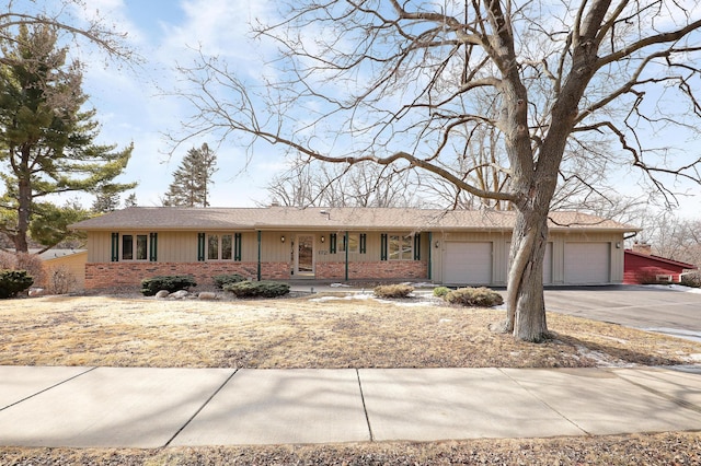 ranch-style house featuring aphalt driveway, brick siding, and an attached garage