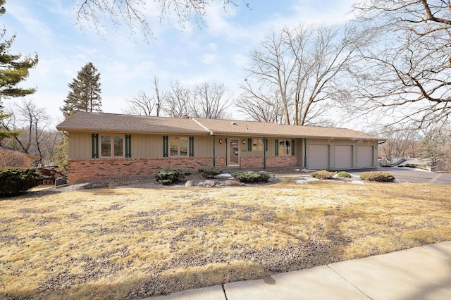 ranch-style house featuring an attached garage, aphalt driveway, and brick siding