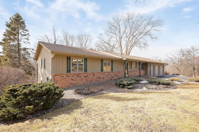 ranch-style house with an attached garage, driveway, board and batten siding, and brick siding