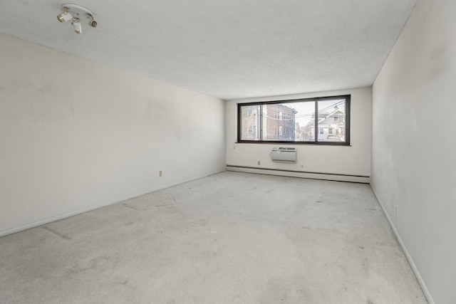 carpeted empty room featuring a baseboard heating unit, a wall mounted AC, and a textured ceiling