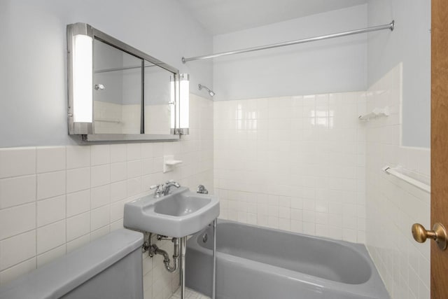 full bathroom with sink, tile walls, toilet, and tiled shower / bath