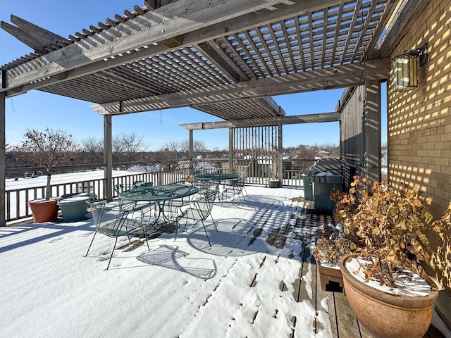 snow covered patio with area for grilling and a pergola